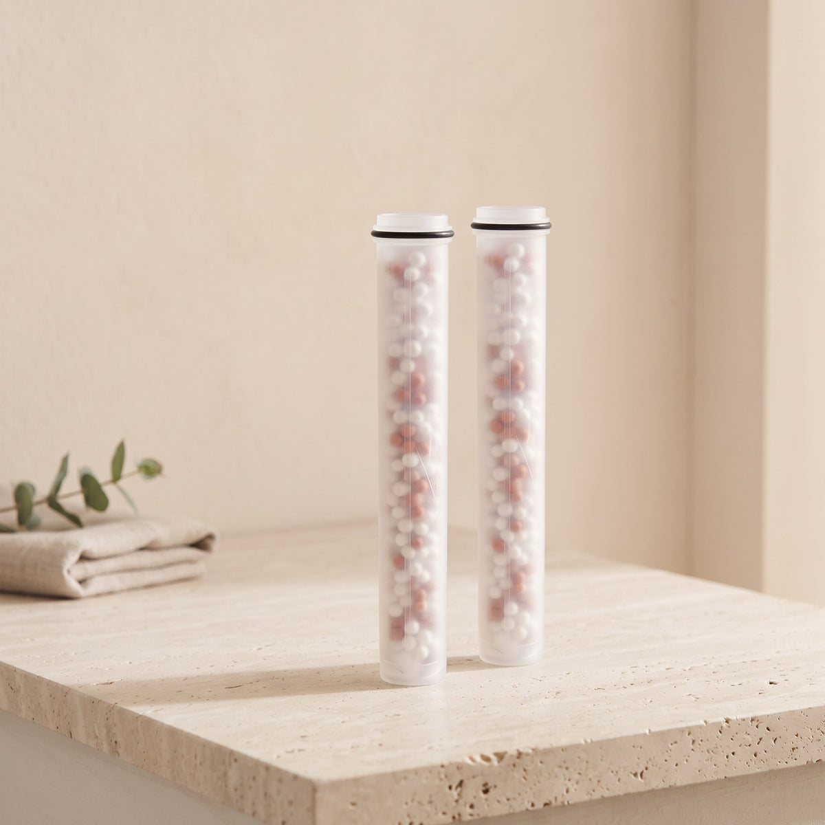Illustration: two Driftrain refill cartridges standing on a travertine bathroom ledge (AI-made image)