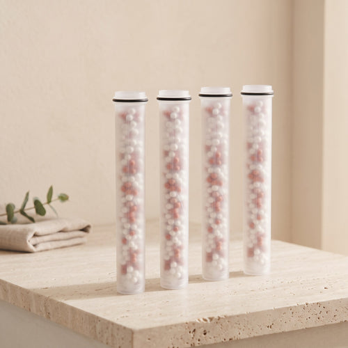 Illustration: four Driftrain refill cartridges in a row on a travertine bathroom ledge (AI-made image)