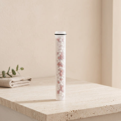 Illustration: one Driftrain refill cartridge standing on a travertine bathroom ledge (AI-made image)