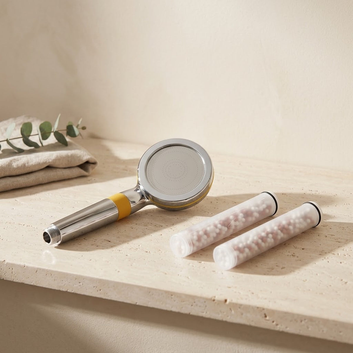 Illustration: the Driftrain handheld with 2 spare cartridges on a travertine bathroom ledge (AI-made image)